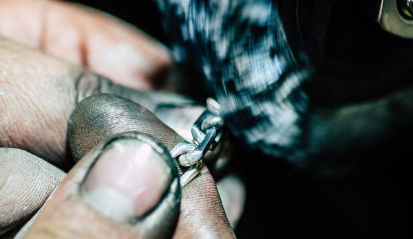 Photo of a craftsman's hands polishing a steel chain, indicating that backlinks are best built by hand