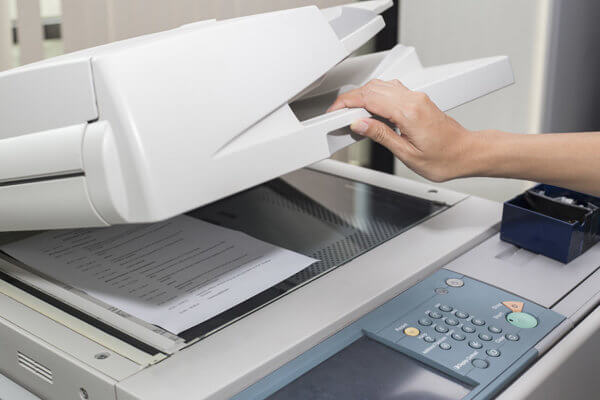 Photo of a person placing a document in a copier to copy it, representing the copy-paste nature of many free SEO audits