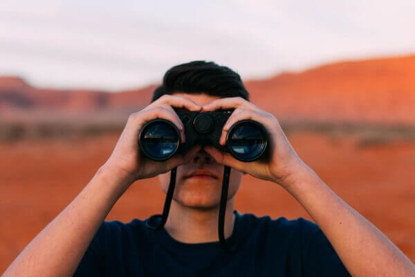 photo of a man with binoculars looking at the camera